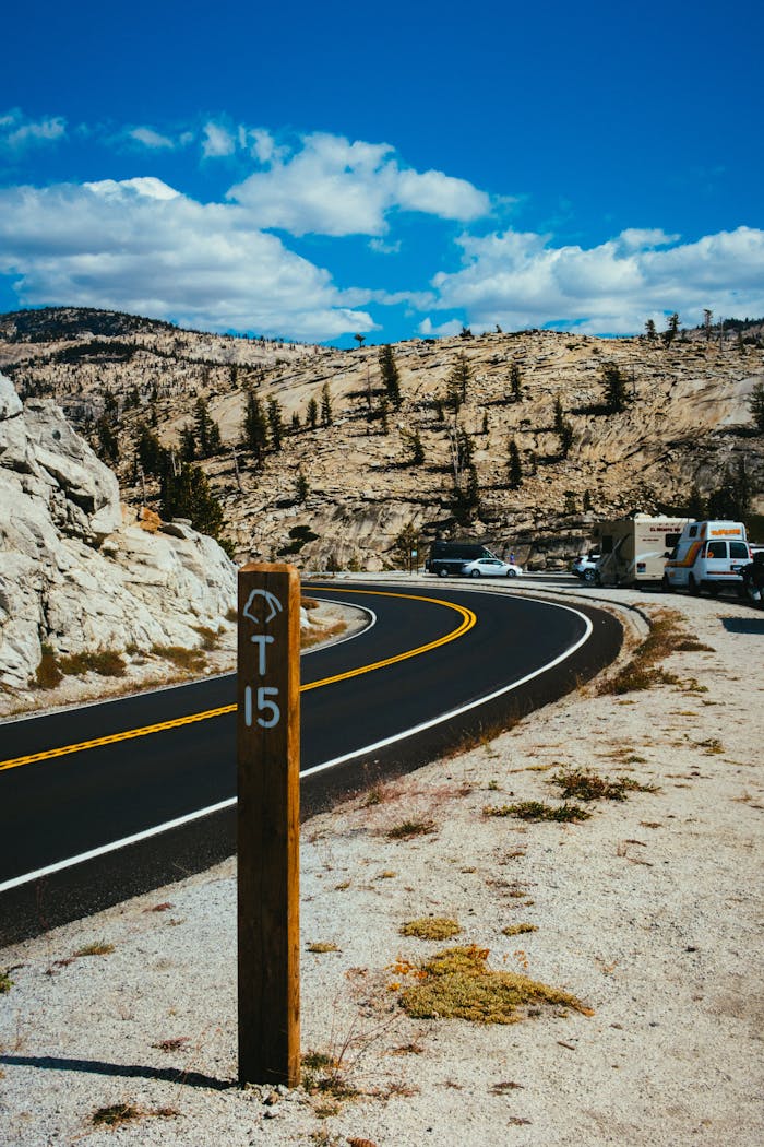 Curvy desert highway with a scenic mountain backdrop and clear blue sky.