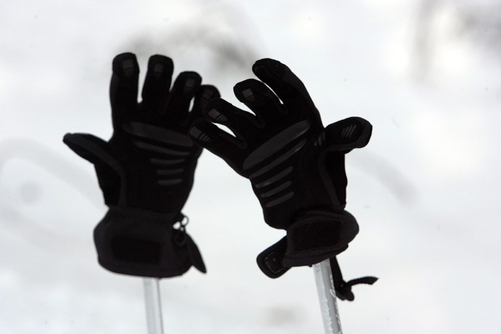 Close-up view of hands wearing rubber gloves removing greasy, blackened fan blades from inside an RV range hood housing. Show