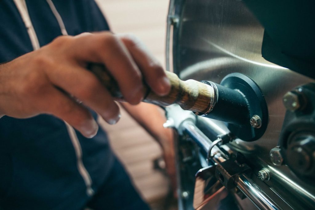 Close-up view of hands adjusting three brass or plastic bypass valves behind an RV water heater, with valve handles clearly s
