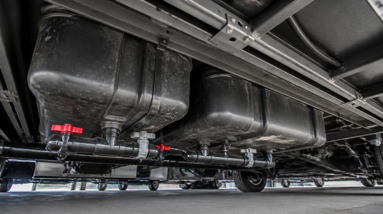 RV black and gray holding tanks mounted beneath motorhome chassis showing drain valves and sewer pipes